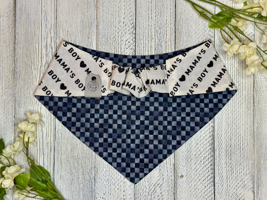Picture of the backside of a pet bandana showing the scrunchie neckline. Displayed on a wooden surface with flowers for decoration.