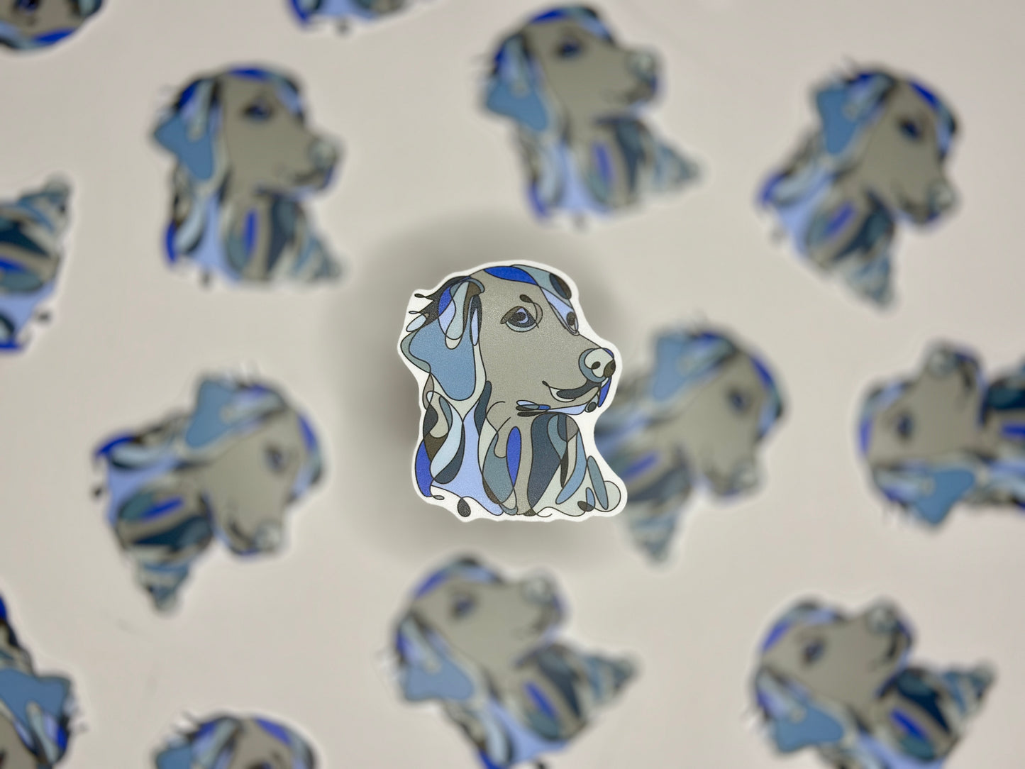 A sticker of a golden retriever in blue and white colors, placed on a background with the same image repeated.