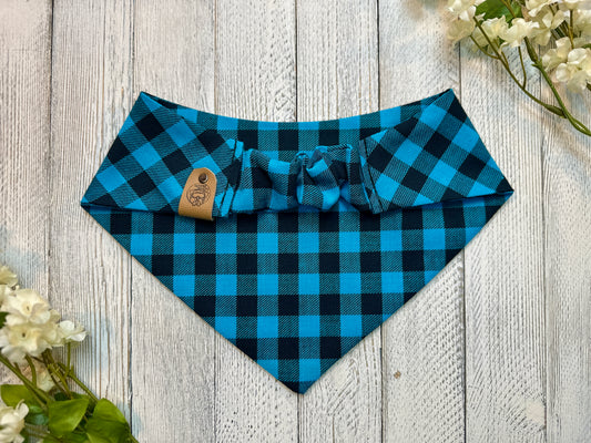 Picture of the backside of a pet bandana showing the scrunchie neckline. Displayed on a wooden surface with flowers for decoration.