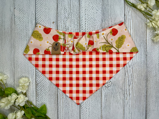 Picture of the backside of a pet bandana showing the scrunchie neckline. Displayed on a wooden surface with flowers for decoration.