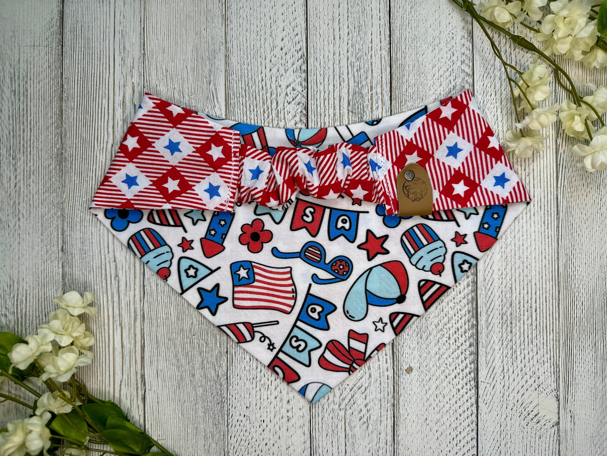 Picture of the backside of a pet bandana showing the scrunchie neckline. Displayed on a wooden surface with flowers for decoration. 