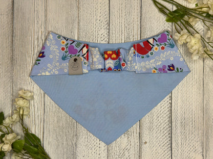 Picture of the backside of a pet bandana showing the scrunchie neckline. Displayed on a wooden surface with flowers for decoration. 
