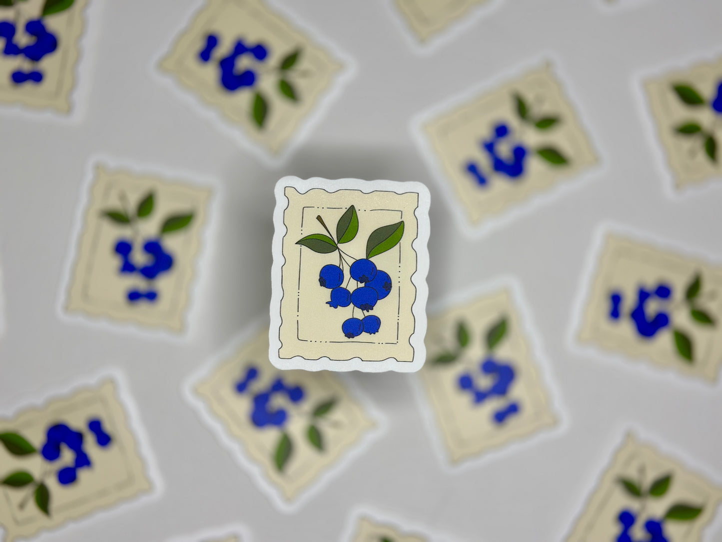 Sticker showing a cream colored stamp with a blueberry drawing 