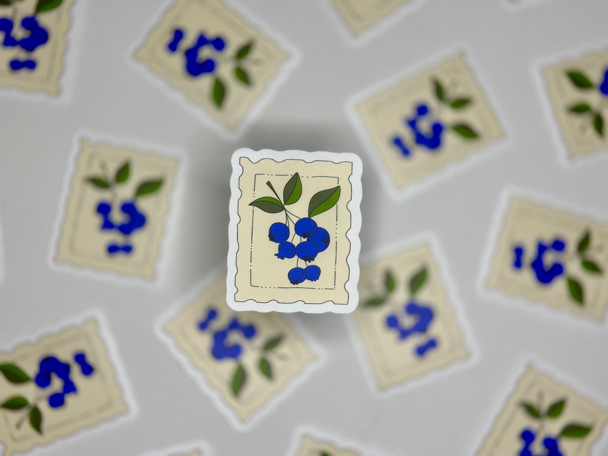 Sticker showing a cream colored stamp with a blueberry drawing 