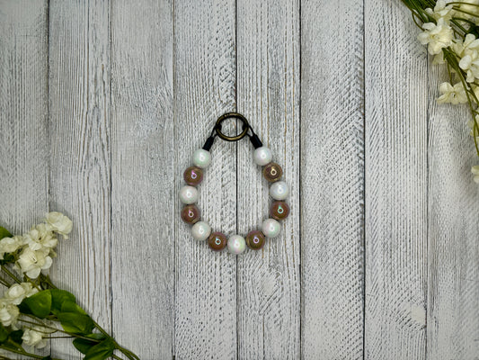 Beaded brown and white pet necklace on a wooden surface with flowers. 