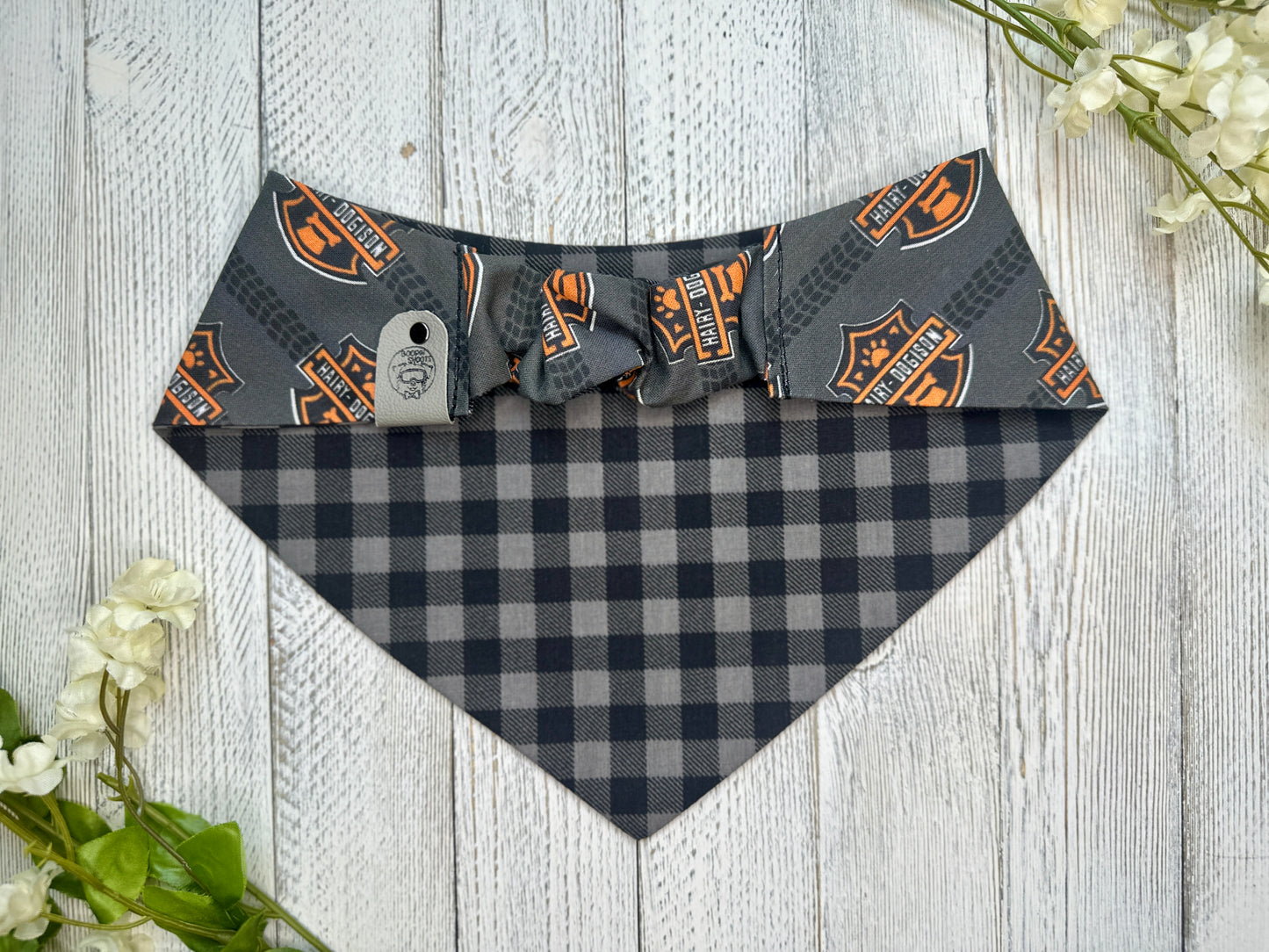 Picture of the backside of a pet bandana showing the scrunchie neckline. Displayed on a wooden surface with flowers for decoration. 