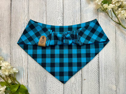 Picture of the backside of a pet bandana showing the scrunchie neckline. Displayed on a wooden surface with flowers for decoration. 
