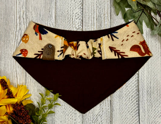 Picture of the backside of a pet bandana showing the scrunchie neckline. Displayed on a wooden surface with flowers for decoration. 
