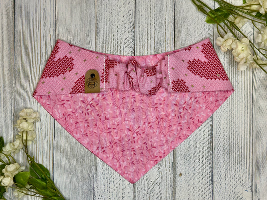 Picture of the backside of a pet bandana showing the scrunchie neckline. Displayed on a wooden surface with flowers for decoration. 