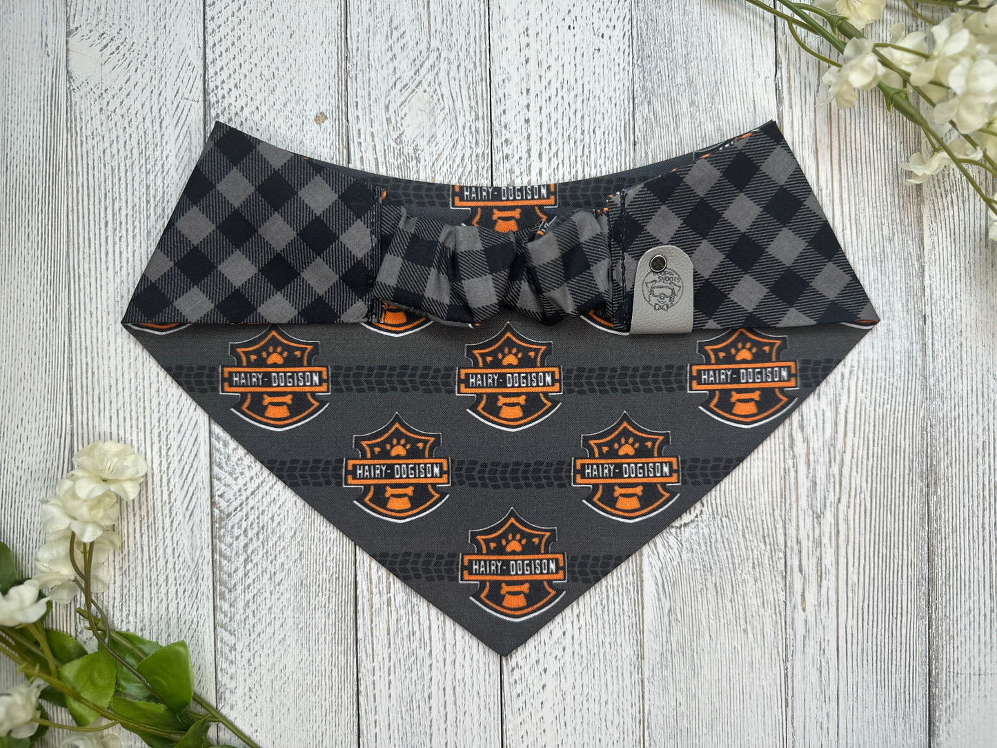Picture of the backside of a pet bandana showing the scrunchie neckline. Displayed on a wooden surface with flowers for decoration. 