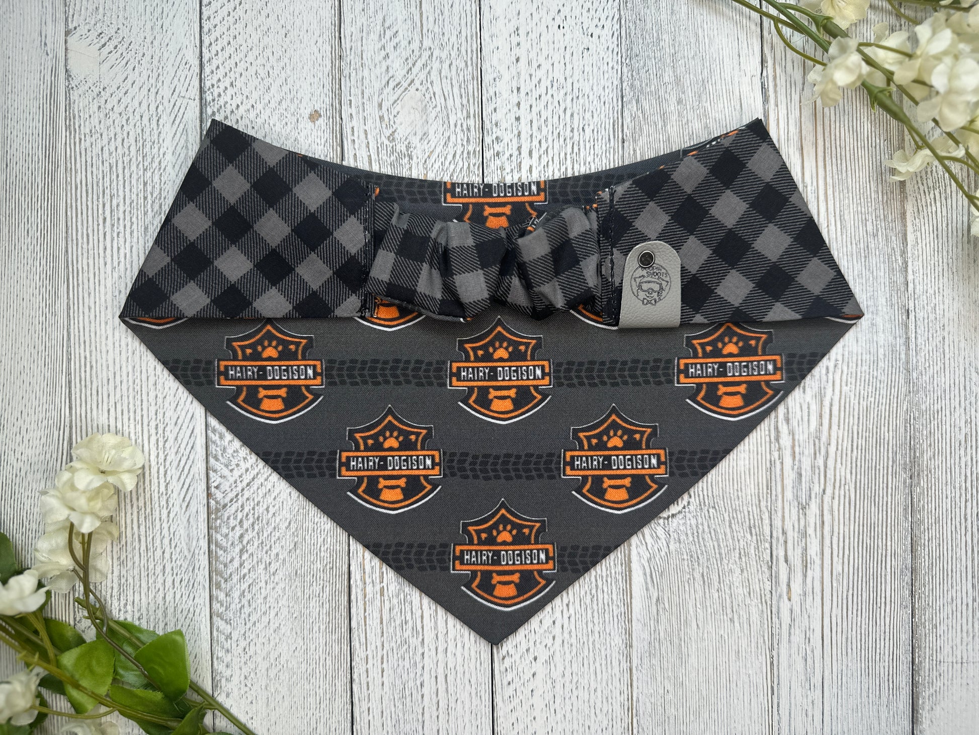 Picture of the backside of a pet bandana showing the scrunchie neckline. Displayed on a wooden surface with flowers for decoration. 