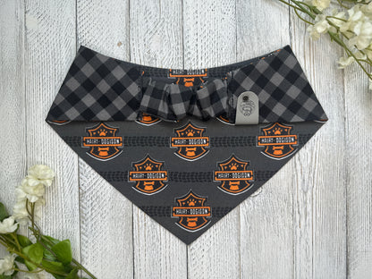 Picture of the backside of a pet bandana showing the scrunchie neckline. Displayed on a wooden surface with flowers for decoration. 