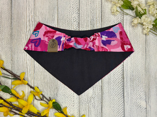 Picture of the backside of a pet bandana showing the scrunchie neckline. Displayed on a wooden surface with flowers for decoration. 