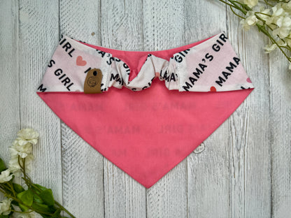 Picture of the backside of a pet bandana showing the scrunchie neckline. Displayed on a wooden surface with flowers for decoration. 