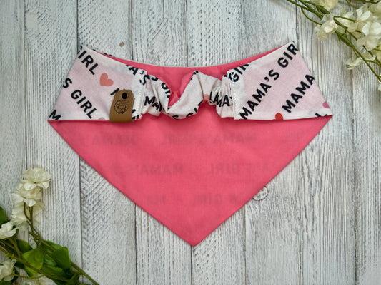 Picture of the backside of a pet bandana showing the scrunchie neckline. Displayed on a wooden surface with flowers for decoration. 