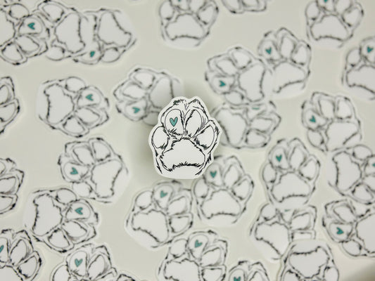 A sticker with a design of a paw print containing a blue heart in the center, placed on a background with the same paw print design.