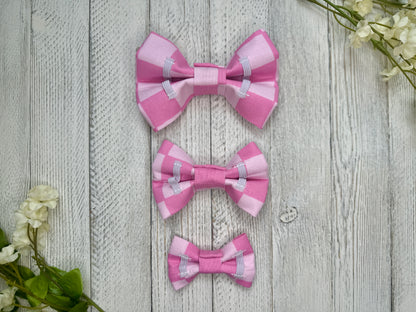 Picture of the backside of pet bow ties showing the elastic straps that fit around a collar. Displayed on a wooden surface with flowers for decoration. 