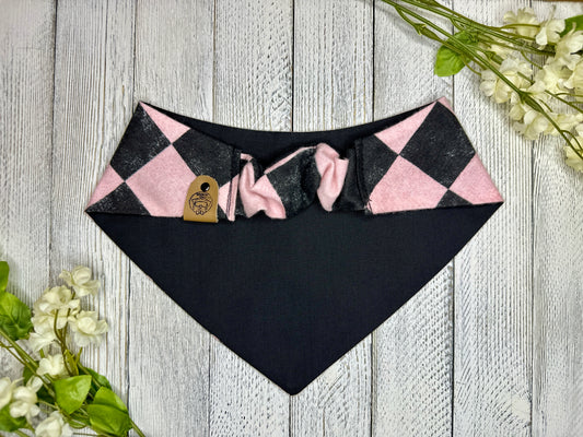 Picture of the backside of a pet bandana showing the scrunchie neckline. Displayed on a wooden surface with flowers for decoration. 