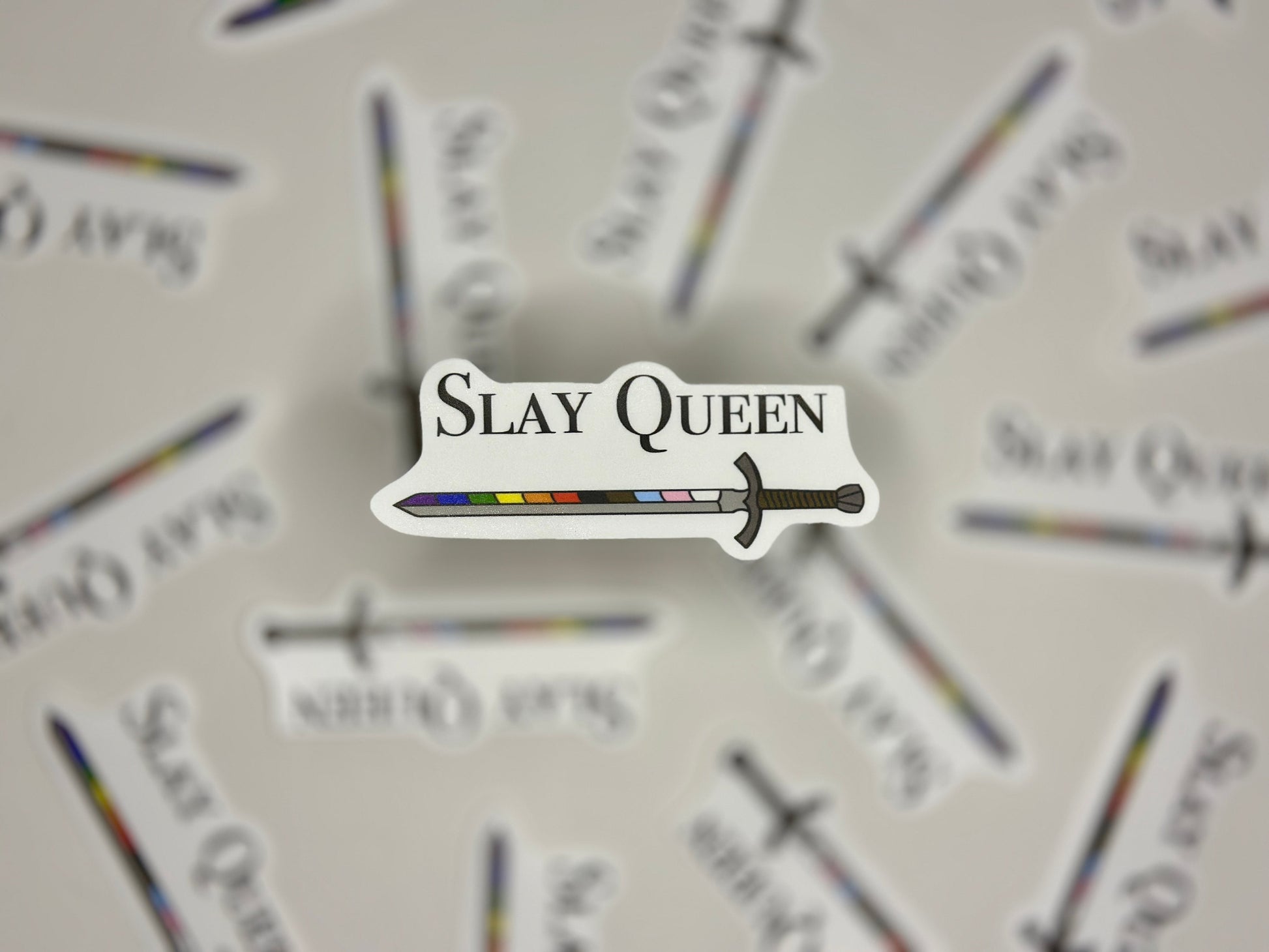 Sticker with 'Slay Queen' text and sword graphic on a blurred background of similar stickers.