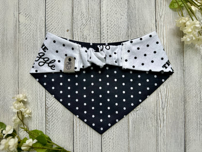 Picture of the backside of a pet bandana showing the scrunchie neckline. Displayed on a wooden surface with flowers for decoration. 