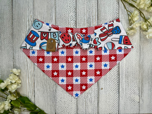 Picture of the backside of a pet bandana showing the scrunchie neckline. Displayed on a wooden surface with flowers for decoration. 