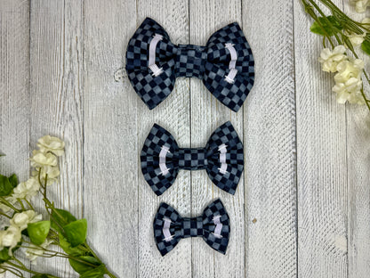 Picture of the backside of pet bow ties showing the elastic straps that fit around a collar. Displayed on a wooden surface with flowers for decoration. 