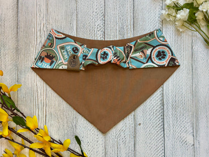 Picture of the backside of a pet bandana showing the scrunchie neckline. Displayed on a wooden surface with flowers for decoration. 